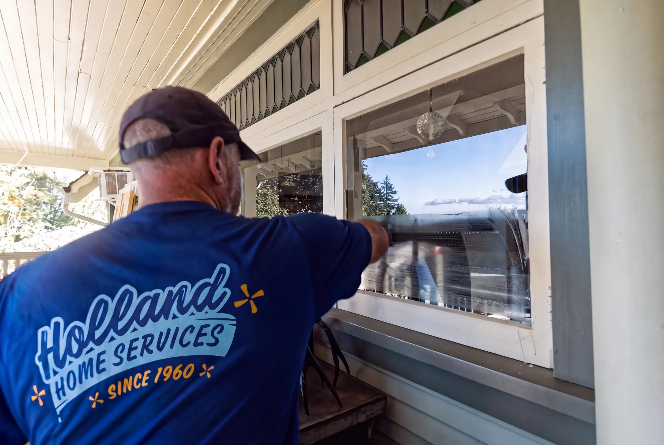 Holland Home Services crew member squeegeeing a window overlooking the water