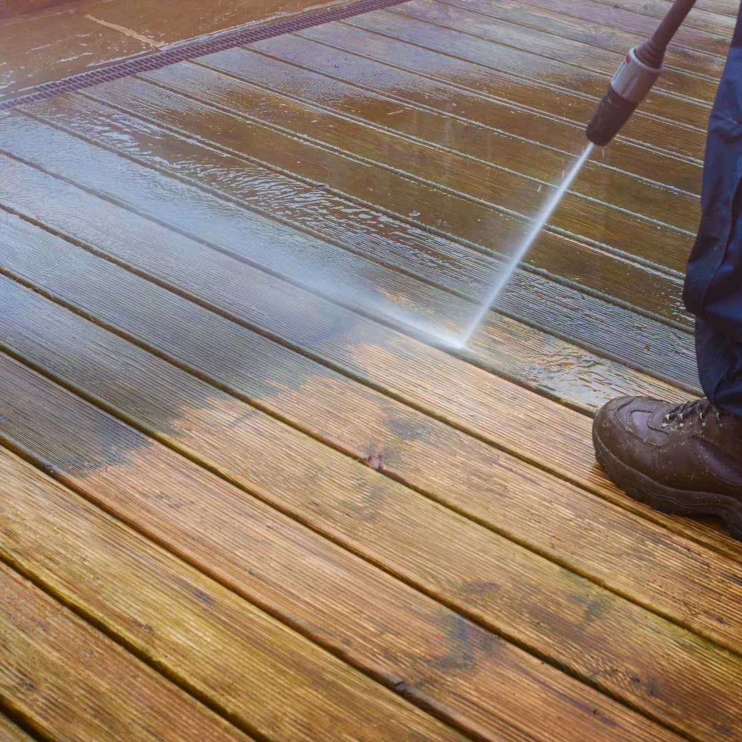 Pressure washer cleaning a wood deck